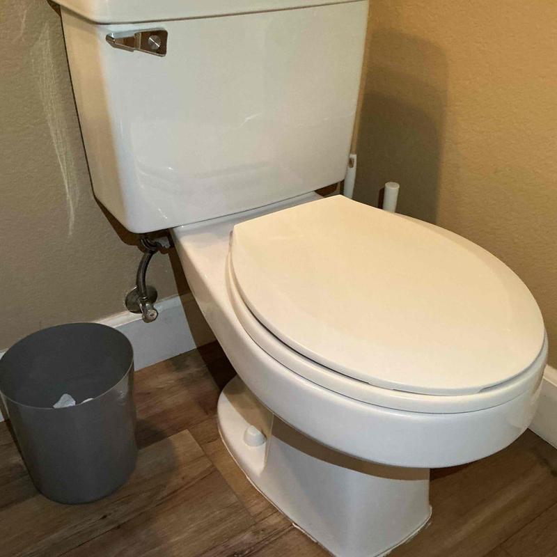 Toilet installation with new hardware in bathroom corner