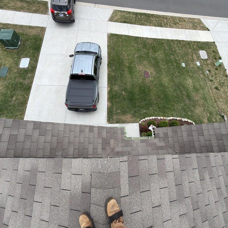 Roof shingles inspection from rooftop with driveway below