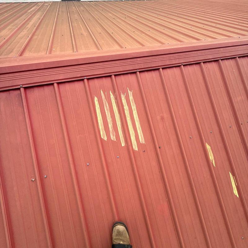 Metal roof panel with hail damage marks and scratches