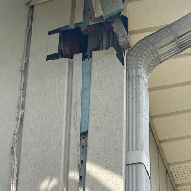 Vinyl siding damage and gutter downspout at corner panel