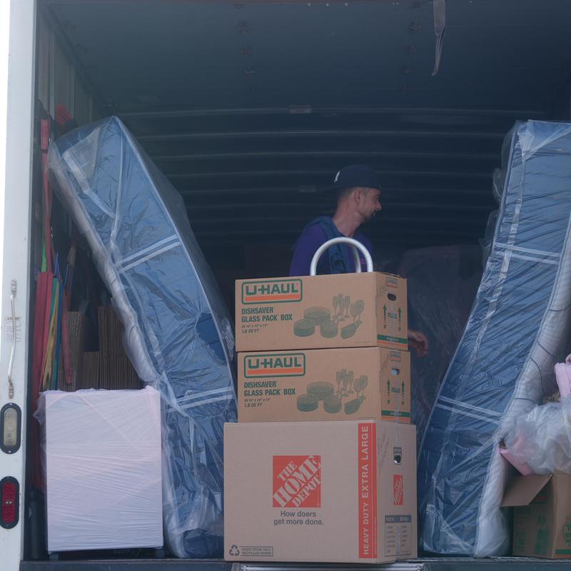 Moving truck interior with wrapped mattresses and packed boxes