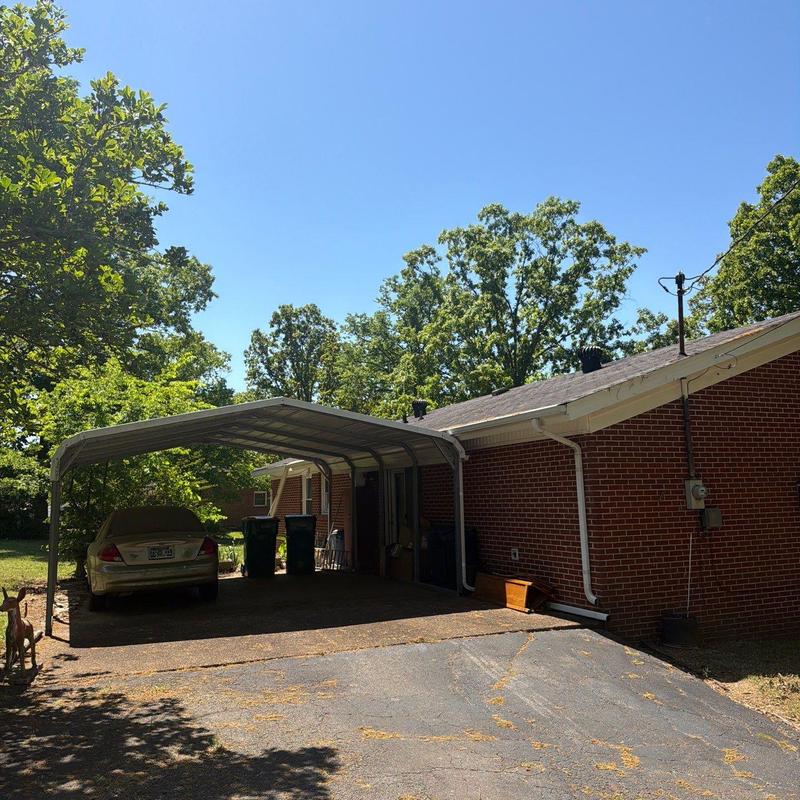 Carport metal frame and roof beside brick house