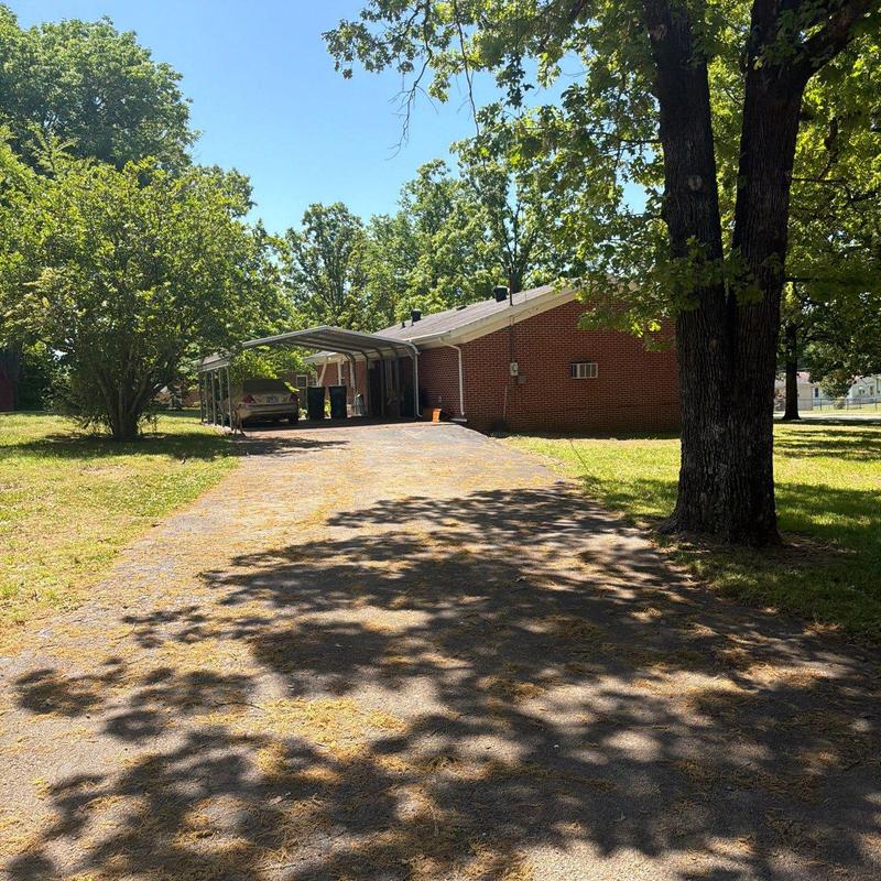 Asphalt driveway with tree shadows and brick house