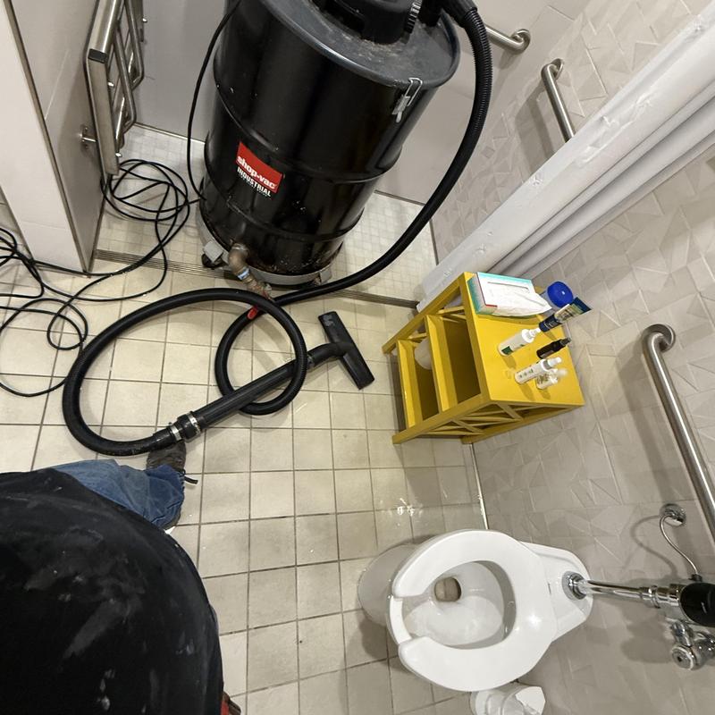Toilet and drain cleaning vacuum in commercial bathroom Toilet and drain cleaning vacuum in commercial bathroom