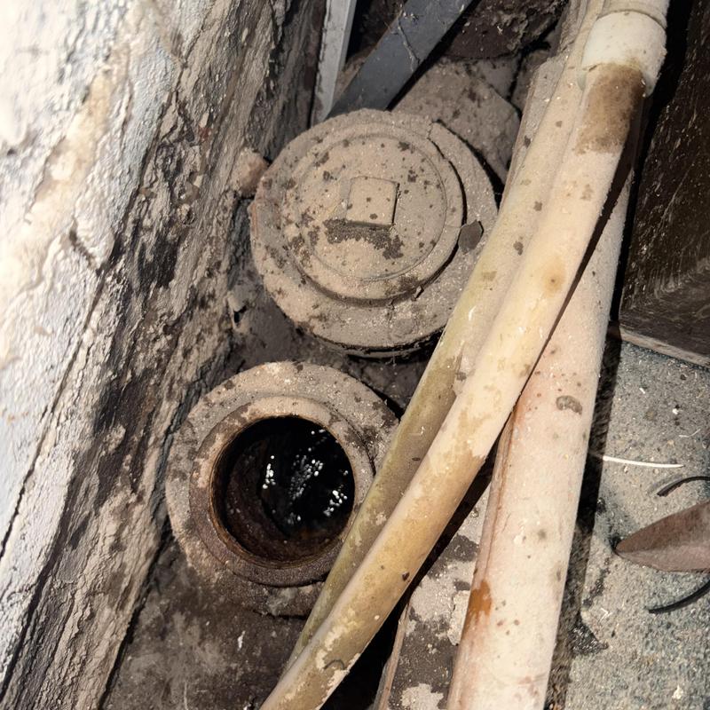 Sewer cleanout access with pipes in dusty wall cavity Sewer cleanout access with pipes in dusty wall cavity