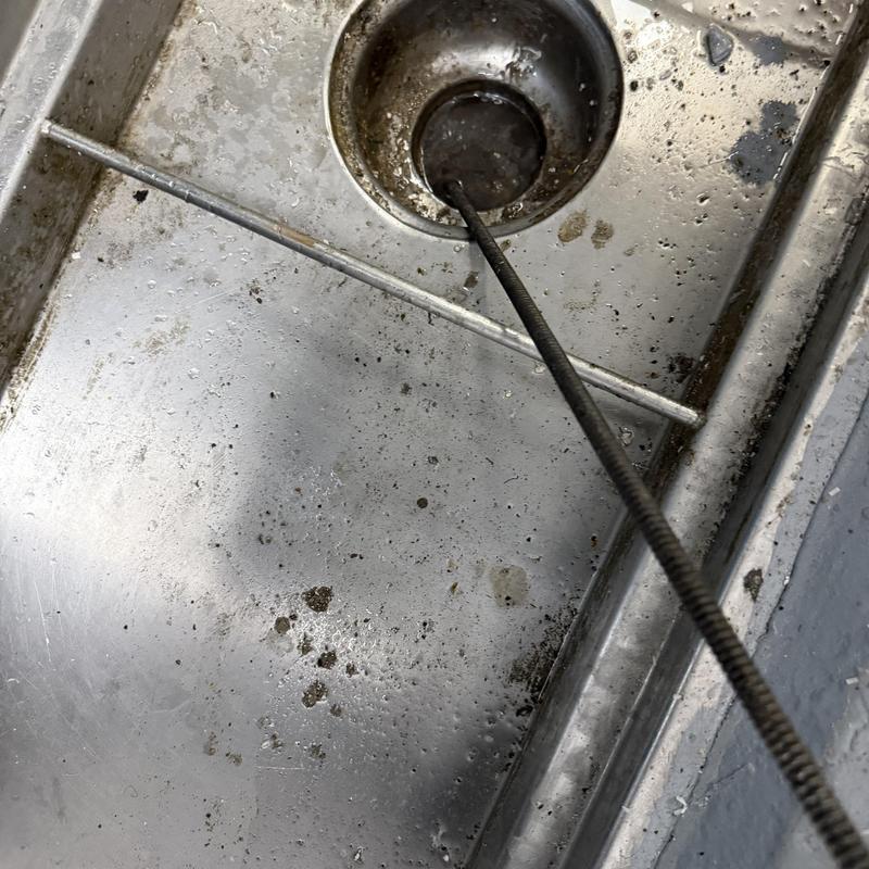 Main line drain cleaning with auger in commercial sink Main line drain cleaning with auger in commercial sink