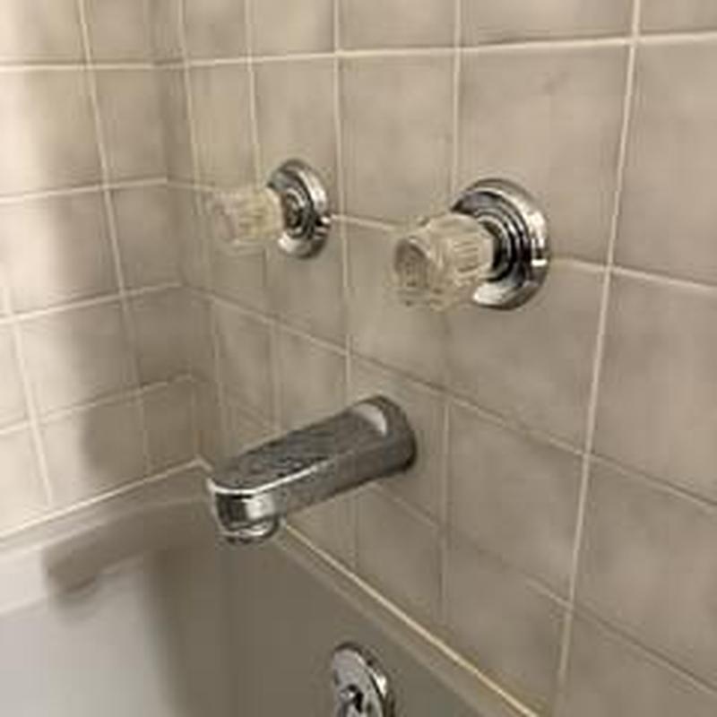 Shower faucet and handles on tiled bathtub wall
