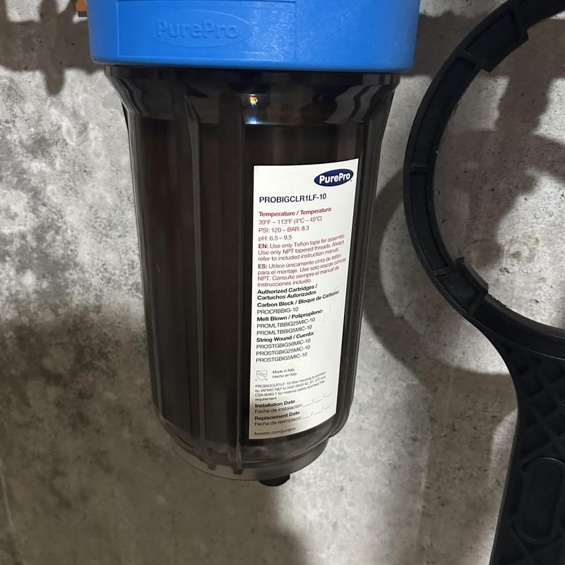 Whole house water filter cartridge and wrench on floor Whole house water filter cartridge and wrench on floor