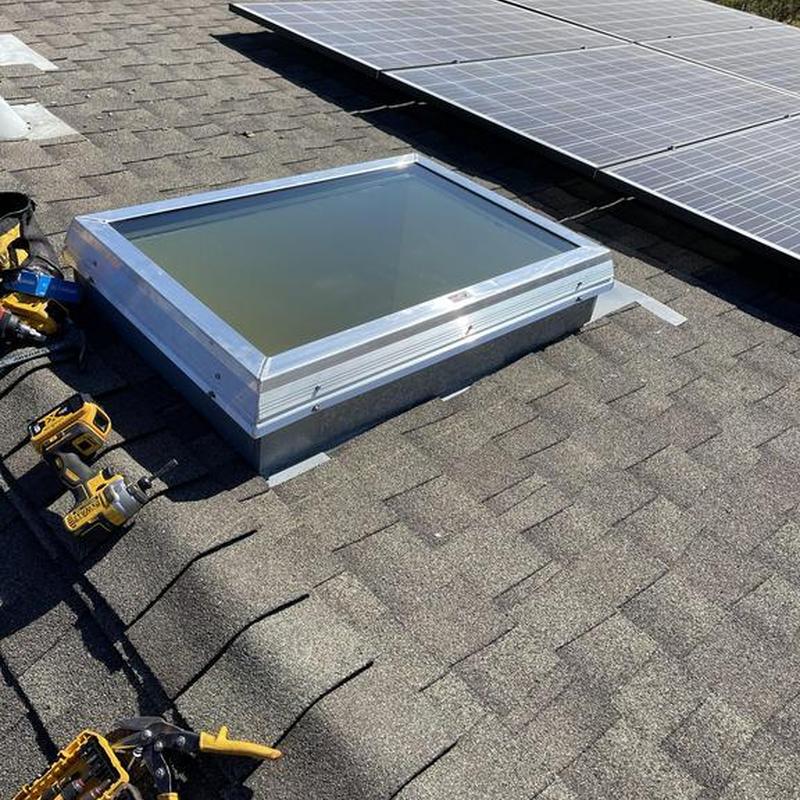 Velux skylight installation on asphalt roof with solar panels