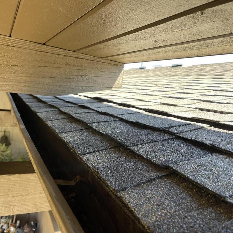 Asphalt roof shingles with repaired edge near soffit