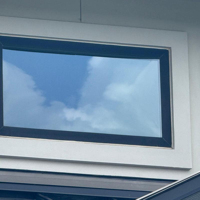 Skylight window with white frame and blue sky reflection Skylight window with white frame and blue sky reflection
