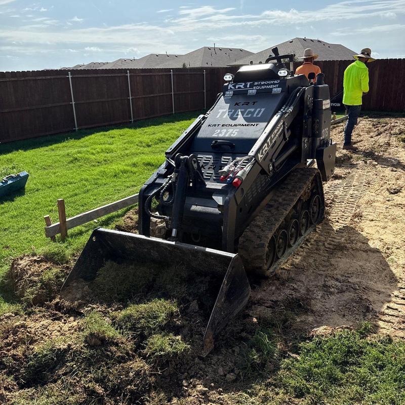 Compact track loader digging soil on residential lawn Compact track loader digging soil on residential lawn