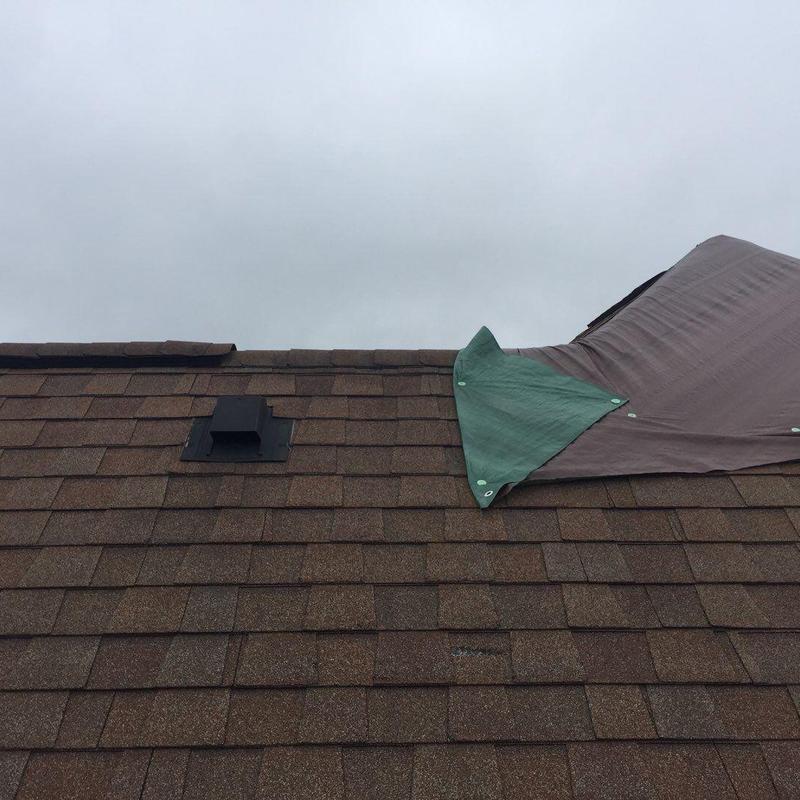 Shingle roof with protective tarp over damaged area