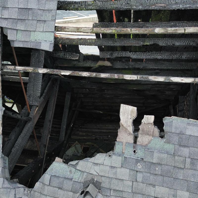 Roof framing with severe fire damage and missing shingles Roof framing with severe fire damage and missing shingles