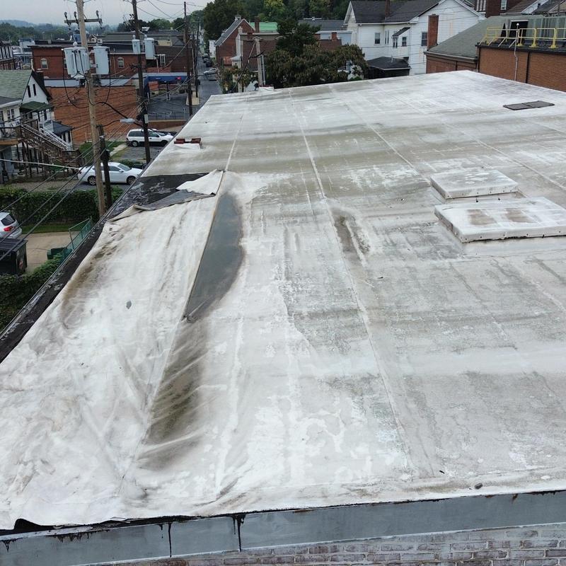 EPDM commercial roof with wind damage and pulling edges EPDM commercial roof with wind damage and pulling edges