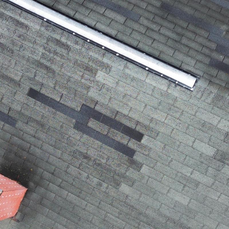 Asphalt shingle roof with dark patch damage Asphalt shingle roof with dark patch damage