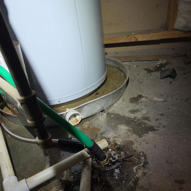 Water heater drain pipe with hose in basement corner