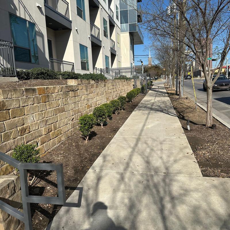 Concrete sidewalk with landscaping and stone wall Concrete sidewalk with landscaping and stone wall