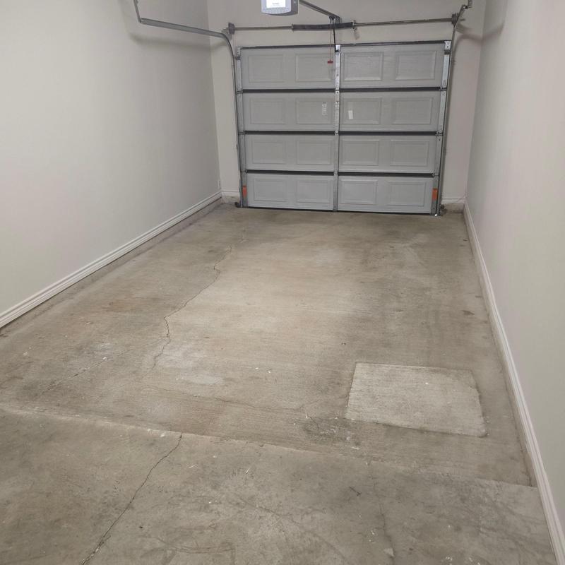 Concrete garage floor with visible cracks and patch Concrete garage floor with visible cracks and patch