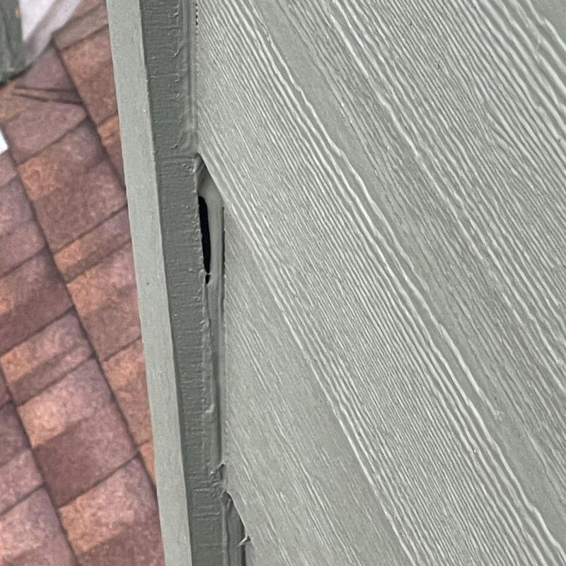 Siding gap and damage near shingle roof edge Siding gap and damage near shingle roof edge