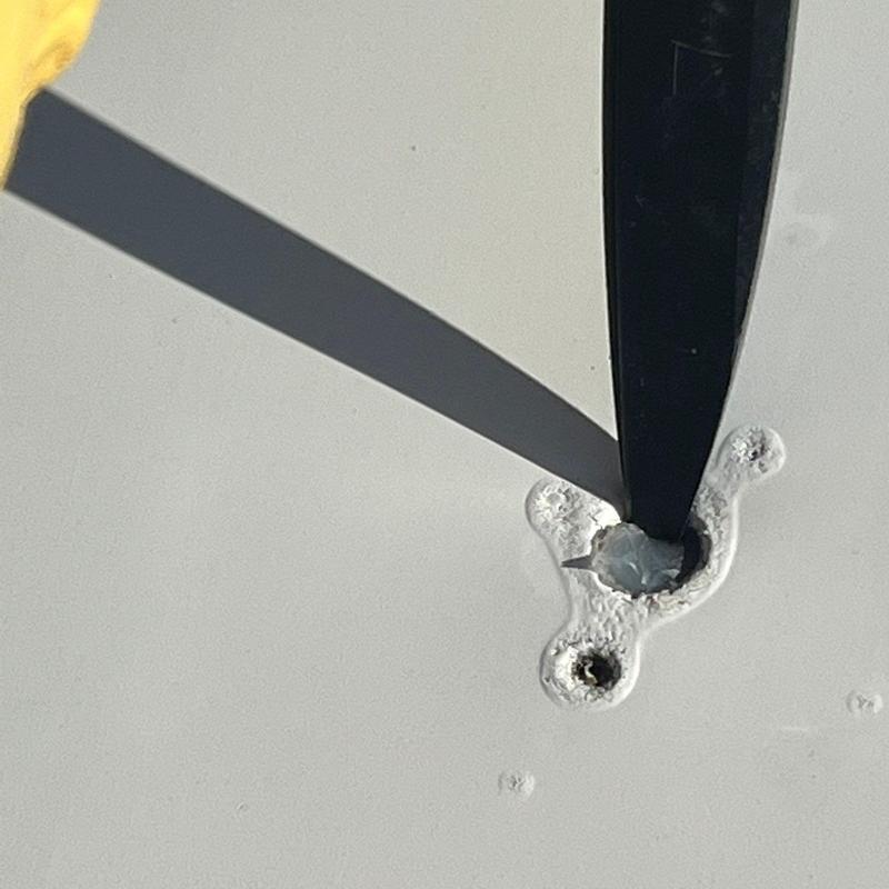 Concrete roof fastener hole with removed screw and tool Concrete roof fastener hole with removed screw and tool