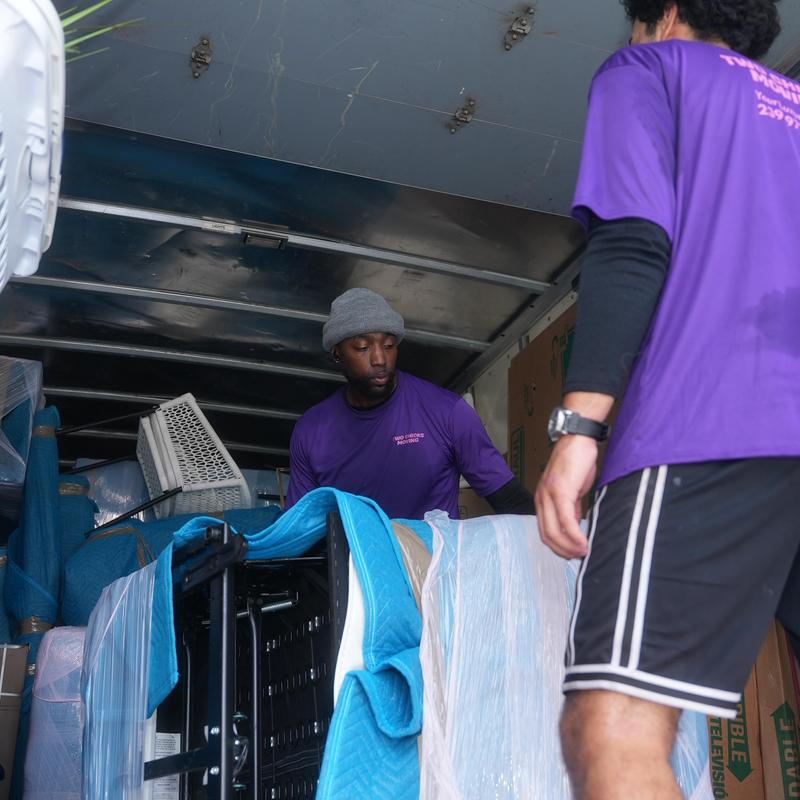 Movers loading wrapped furniture into moving truck