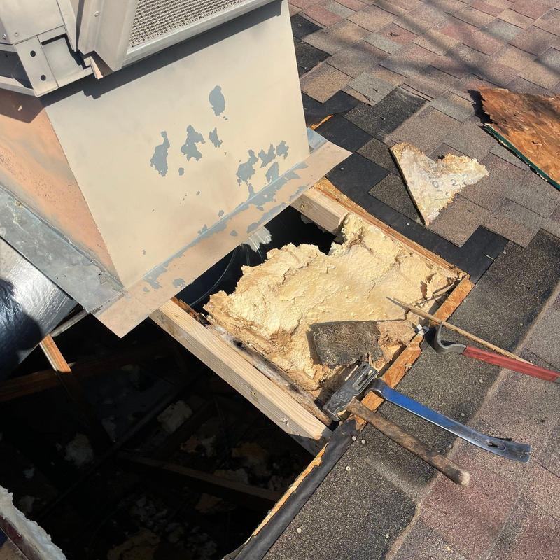 Shingle roof section with exposed damaged insulation and tools Shingle roof section with exposed damaged insulation and tools