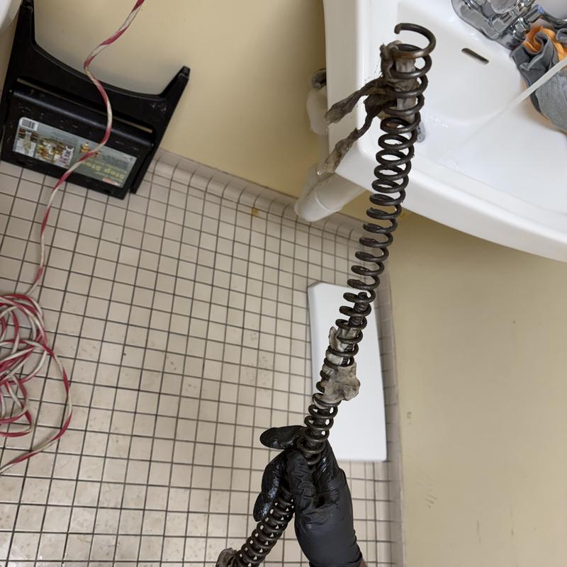Toilet drain auger with debris removal in bathroom Toilet drain auger with debris removal in bathroom