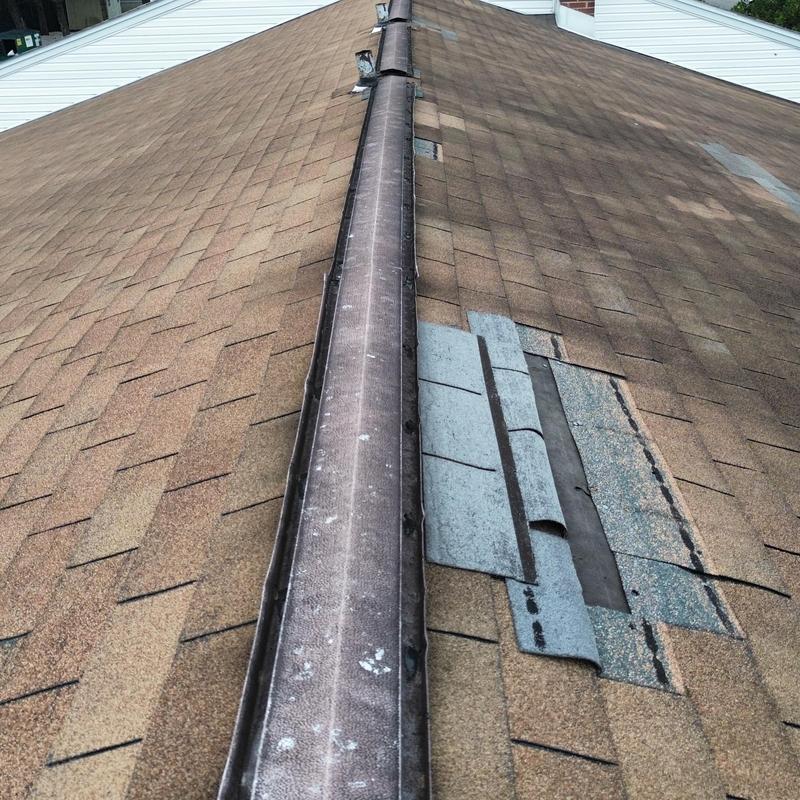 Asphalt shingle roof with damaged patch near ridge cap Asphalt shingle roof with damaged patch near ridge cap