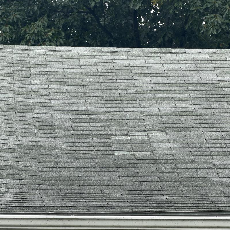 Asphalt shingle roof with wind damage and worn patches Asphalt shingle roof with wind damage and worn patches