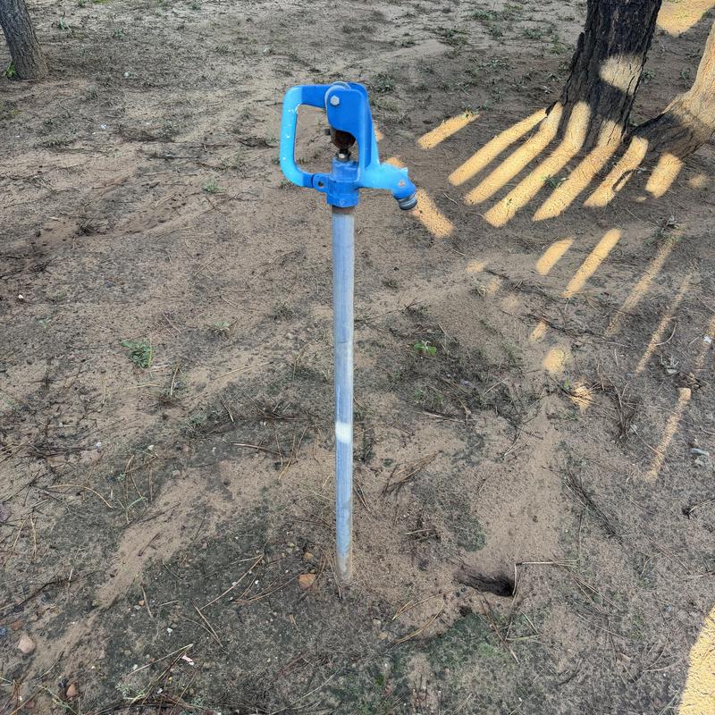 Yard hydrant with blue handle in dry soil Yard hydrant with blue handle in dry soil
