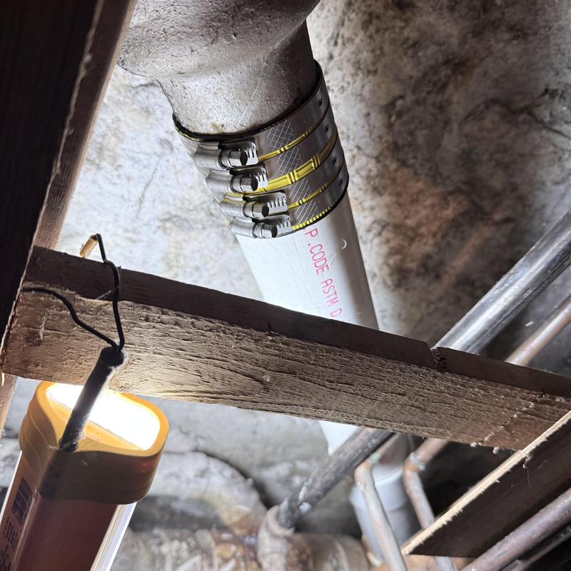 PVC drain pipe with metal clamps in basement ceiling PVC drain pipe with metal clamps in basement ceiling