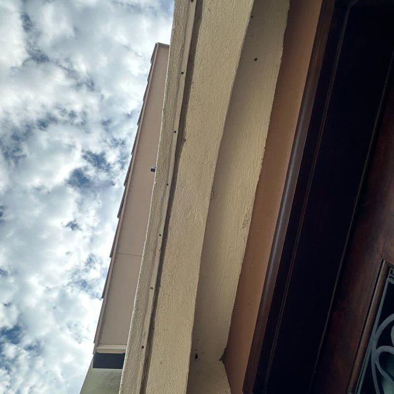 Stucco exterior wall and soffit under cloudy sky Stucco exterior wall and soffit under cloudy sky