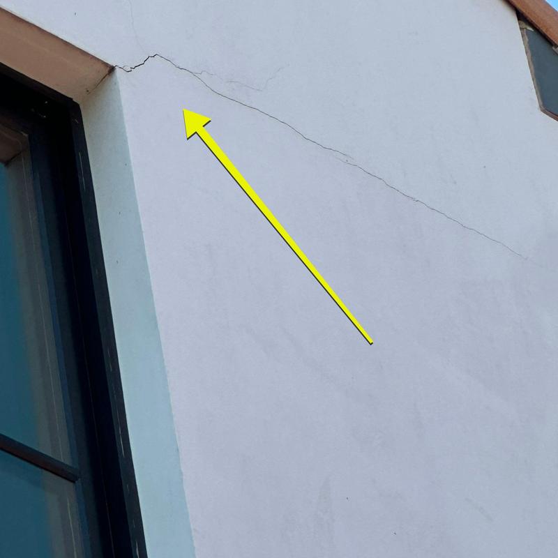 Stucco wall crack near window frame with arrow Stucco wall crack near window frame with arrow