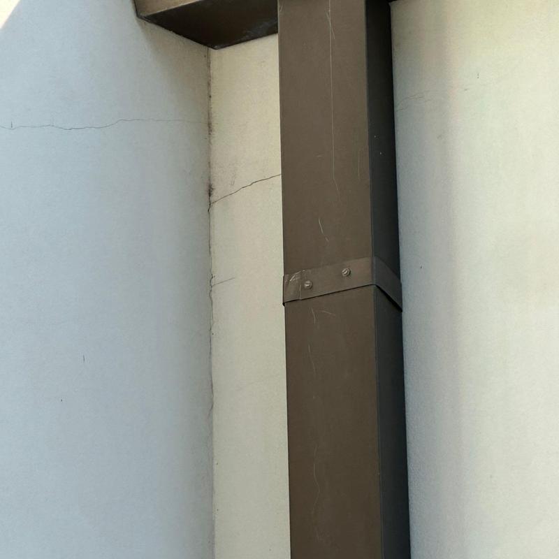 Stucco wall cracks near roof and downspout structure Stucco wall cracks near roof and downspout structure