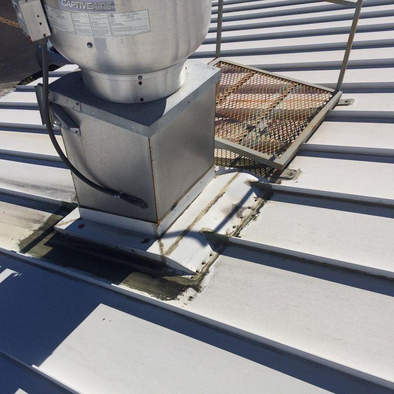 Commercial metal roofing around rooftop vent base