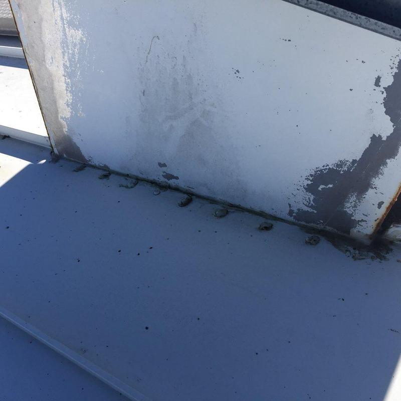 Metal roof seam with rust and sealant buildup