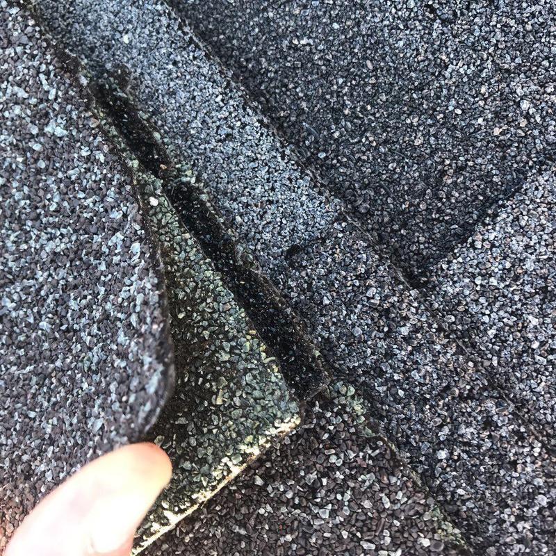 Charcoal-gray shingle roof with lifted damaged tabs