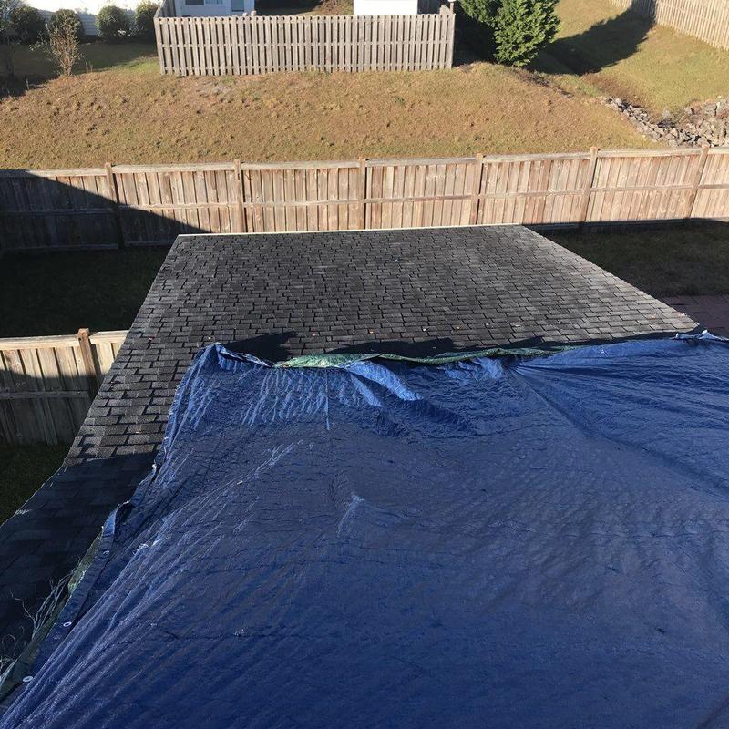Shingle roof with blue tarp covering exposed area