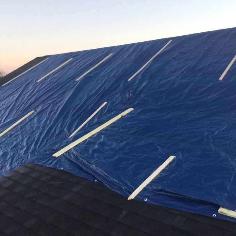 Shingle roof with blue tarp secured by wood battens