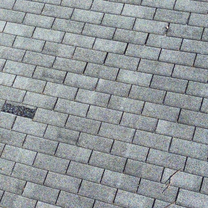 Asphalt shingle roof with visible damage and wear Asphalt shingle roof with visible damage and wear