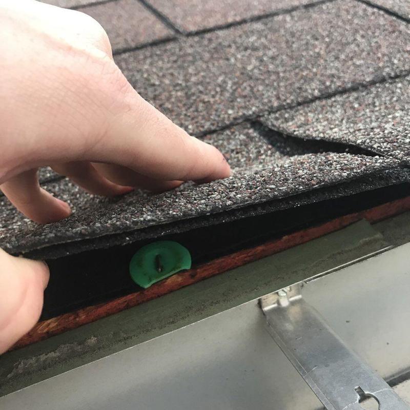 Shingle roof with loose fastener on edge near gutter