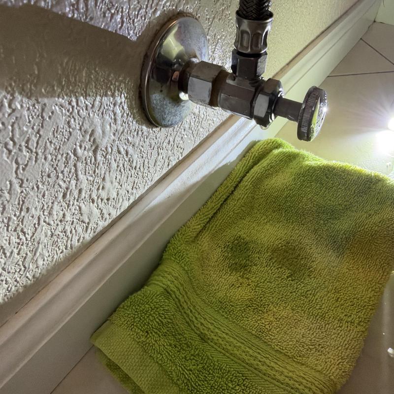 Single angle stop valve beside bathtub with green towel