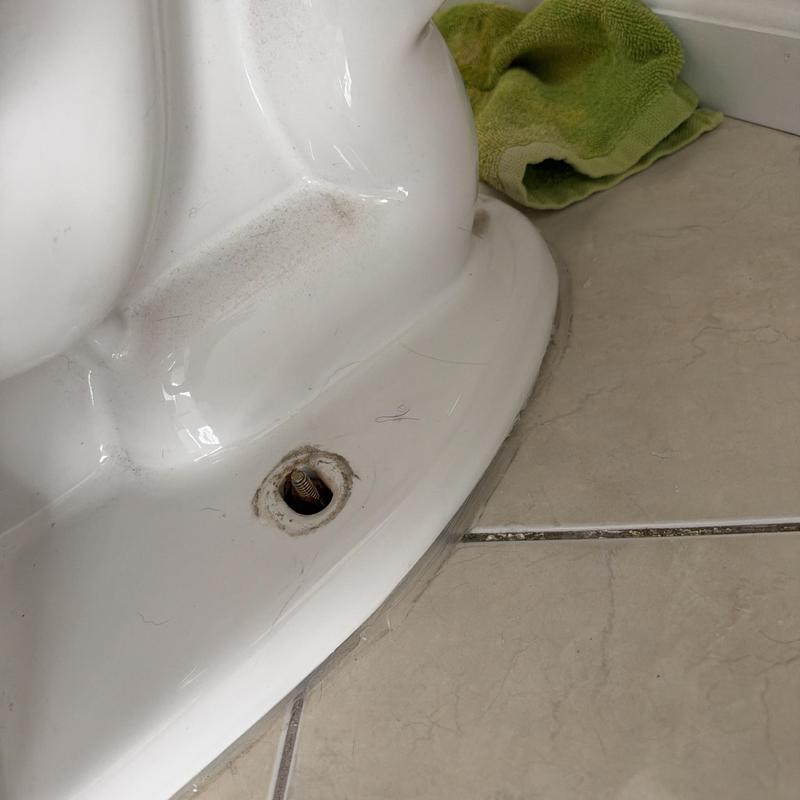 Toilet base bolt and bathroom floor tile close-up