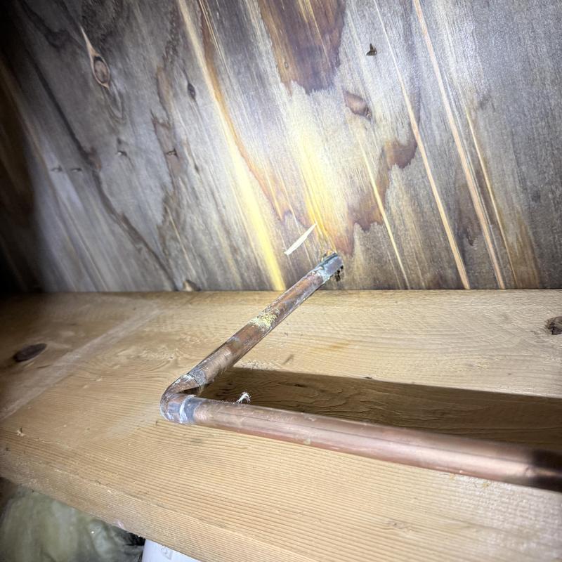 Copper piping with pinhole leak on wooden beam Copper piping with pinhole leak on wooden beam