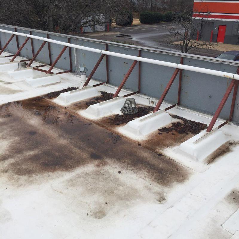 Low-slope roof drain area with rust and debris buildup