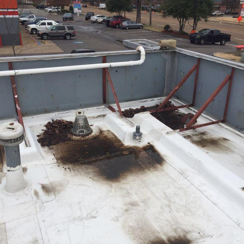 Roof drain area with debris and stains on low-slope roof