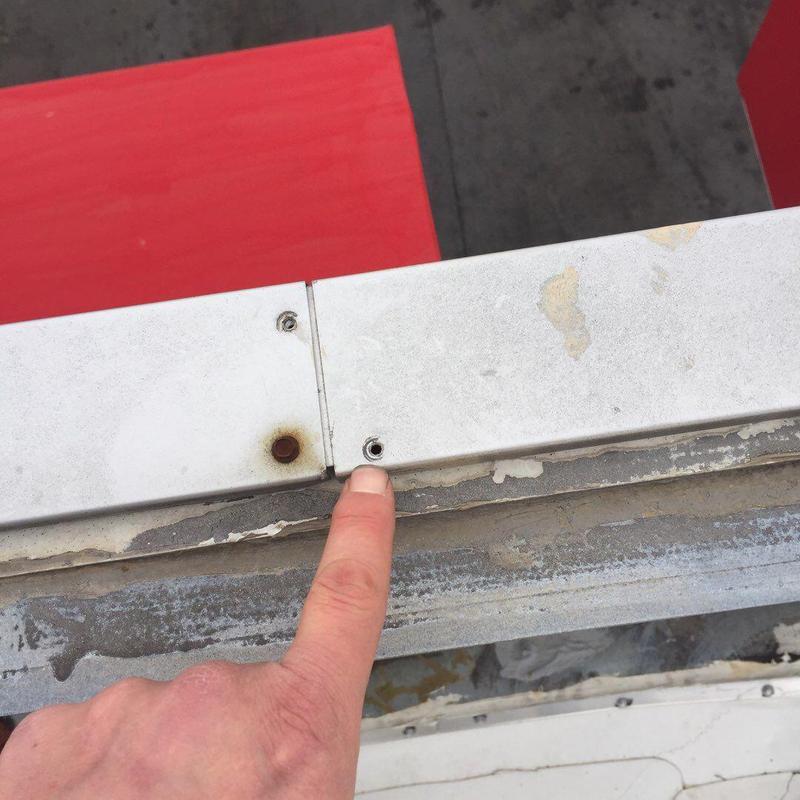 Metal roof edge panels with missing screw at roof perimeter