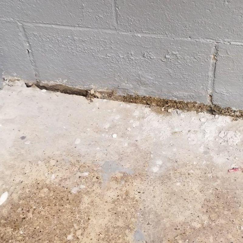 Concrete slab edge with soil gap near wall base Concrete slab edge with soil gap near wall base