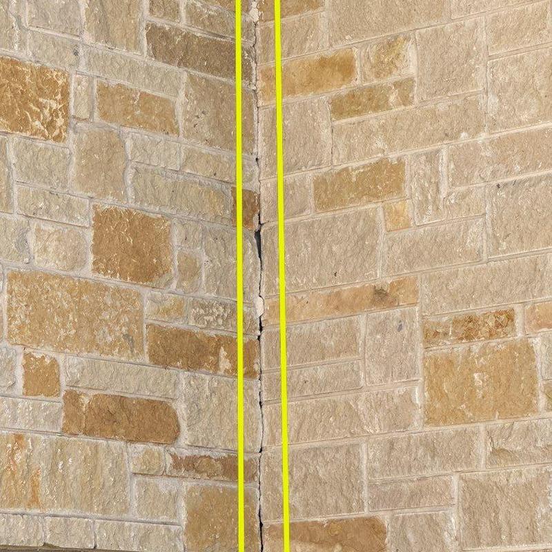 Concrete wall crack in stone veneer exterior Concrete wall crack in stone veneer exterior